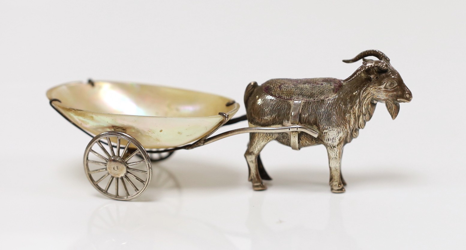 A George V silver and mother of pearl mounted novelty pin cushion, modelled as a goat pulling a cart, Adie & Lovekin, Birmingham, 1911, 11.2cm.